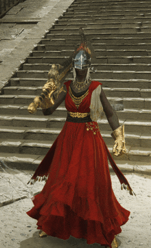 a woman in a red dress and gold gloves is holding a sword