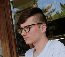 a young man wearing glasses and a white shirt