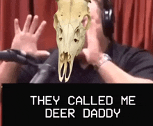 a man with a deer skull on his head is talking into a microphone .