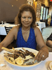 a woman in a blue dress is sitting at a table with a plate of food