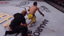 a referee is kneeling down in front of a sign that says ufc on it