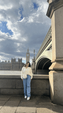 a woman in a white sweater stands in front of big ben in london