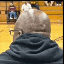 a man in a black hoodie is watching a basketball game with a woman in a wheelchair