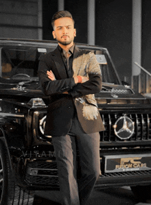 a man in a suit stands in front of a mercedes benz