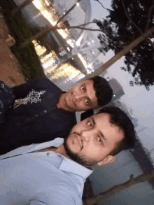 two men are posing for a picture in front of a body of water at night