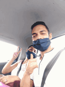 a man and a woman in a car wearing face masks