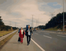 a man and a woman are walking down a road