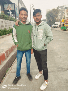 two young men standing next to each other with one wearing a rainbow hoodie