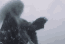 a blurry picture of a person standing in the snow holding a gun .