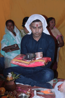 a man wearing a head scarf holds a box that says " nokia " on it