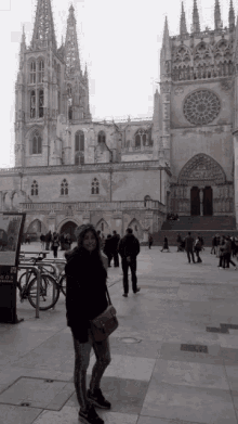 a woman stands in front of a large building with a sign that says ' plaza de espana ' on it