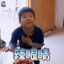 a young boy is sitting at a table with a bowl of strawberries in front of him with chinese writing on it .