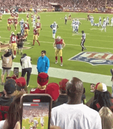 a group of people watching a football game with a man wearing a hat that says ' ucsd ' on it