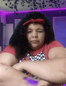 a woman with curly hair wearing a red shirt and a red bow on her head