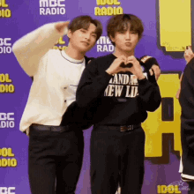 two young men are making a heart shape with their hands in front of a sign that says mbc radio