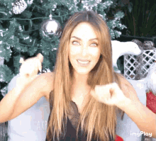 a woman is standing in front of a christmas tree with the word axp on the pillow in the background