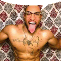 a shirtless man with glasses and tattoos on his chest is sticking his tongue out .