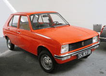 a red peugeot car with a license plate that says 104 ber 68