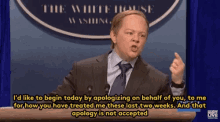 a man in a suit and tie is giving a speech at a podium in front of the white house