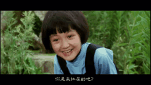 a little girl in a blue shirt is smiling with chinese writing below her