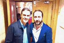 two men posing for a picture in front of a door