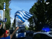 a blue and white flag is being waved in front of a bus that says que bien sabia ser del lega