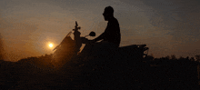 a silhouette of a man riding a motorcycle with the sun behind him