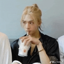 a man with blonde hair is drinking from a cup with a straw .