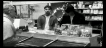 a black and white photo of a man behind a counter in a store with a jar that says 20 on it