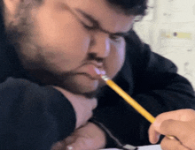 a man with a pencil in his mouth is writing