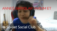 a boy wearing headphones and a blue shirt is sitting in front of a sign that says sovyet social club