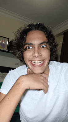 a young man with curly hair and braces on his teeth makes a funny face