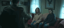 a man is standing in front of two people sitting on a couch in a living room .