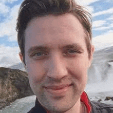 a close up of a man 's face with a waterfall in the background and a waterfall in the background .