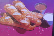 pretzel sticks and dipping sauce on a purple surface