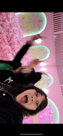 a woman is taking a selfie in front of a wall of pink balls and a sign that says " i love you "