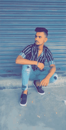 a man in a black and white striped shirt sits on the ground