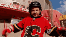 a man wearing a red jersey with the number 3 on it is standing in front of a scotiabank building .