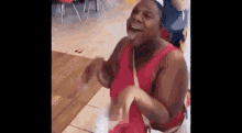 a woman in a red tank top is dancing in a restaurant and laughing .