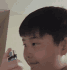 a young boy is holding a blue lighter in his hand and smiling .