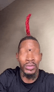 a man with a mohawk and a third eye on his head is taking a selfie .