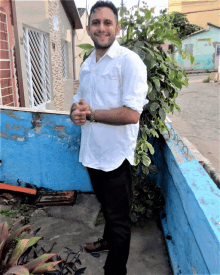 a man in a white shirt and black pants is standing next to a blue wall