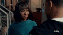 a woman in a blue sweater is looking at a man in a black shirt .