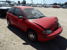 a red car with a broken hood is parked in a parking lot .