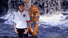 a man wearing a nasa sweatshirt stands next to a tiger