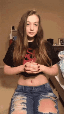 a young woman wearing a crop top and ripped jeans