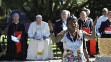 a woman wearing a lanyard with the number 14 on it is standing in front of a group of priests