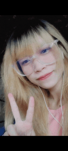 a girl wearing glasses and headphones is giving the peace sign