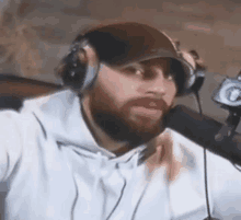 a man with a beard and headphones is talking into a microphone .