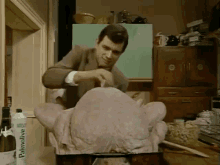 a man is preparing a turkey in a pan next to a palmolive bottle